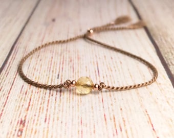May include: A brown cord bracelet with a yellow citrine gemstone and rose gold beads. TranquilityTherapyUK.etsy.com