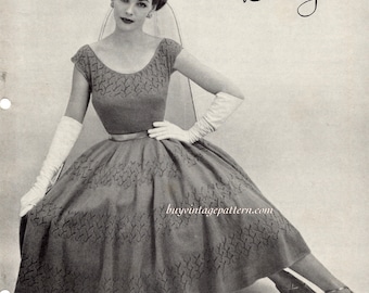 May include: Black and white photo of a woman wearing a knitted dress with a Botany label. The dress has a fitted bodice and a full skirt. The woman is wearing white gloves and heels.