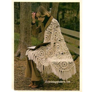 May include: A crocheted throw blanket with a fringe border. The blanket is white with a pattern of circles and is draped over a bench. The blanket is made with a crochet stitch that creates a textured look.