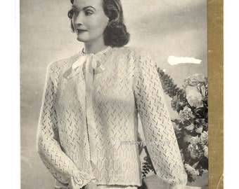 May include: A vintage knitting pattern for a white crocheted cardigan with a bow at the neckline. The pattern is from the 1940s and features a delicate lace design.