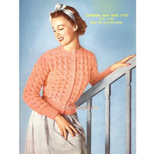 May include: A woman wearing a light pink knitted cardigan with a button-up front. The cardigan has a delicate openwork pattern. The woman is standing on a staircase and holding onto the railing. The text on the image reads "SUNSHINE BABY WOOL 3-PLY TWO SIZES Bust 32 and 38 inches".