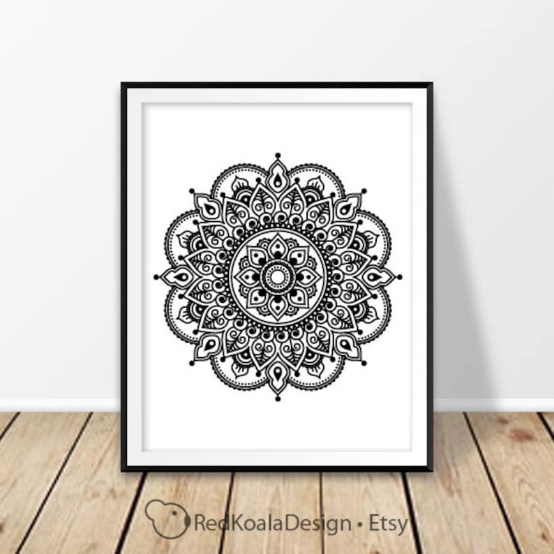 May include: Black and white mandala design print in a black frame. The mandala is intricate and detailed, with a circular pattern of flowers and leaves.