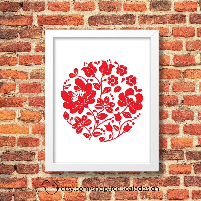 May include: A white framed print with a red floral design in a circle on a white background. The floral design is a traditional Hungarian folk art pattern.