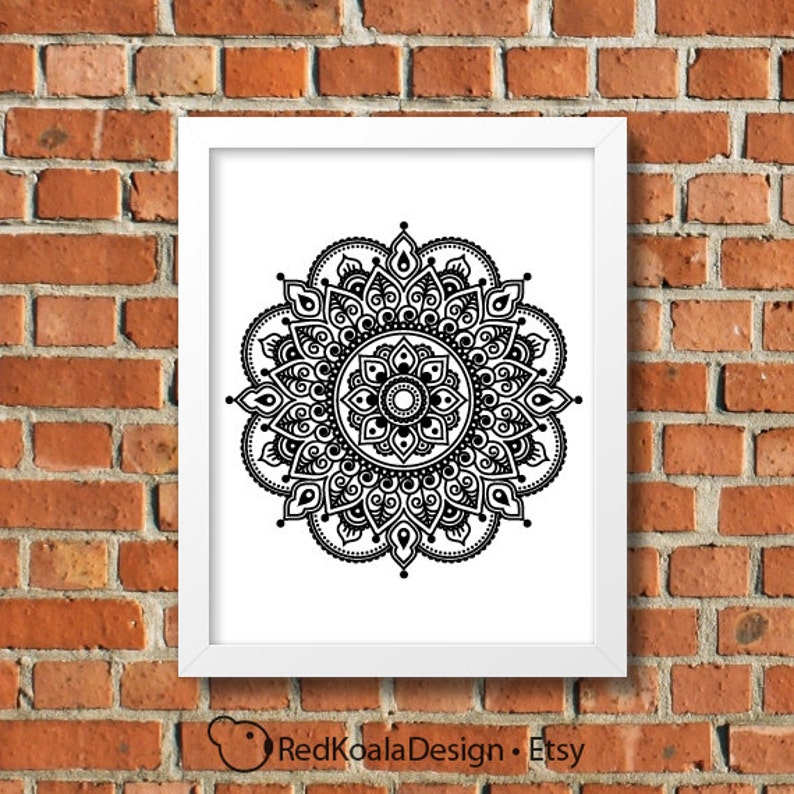May include: Black and white mandala design print in a white frame against a brick wall background.