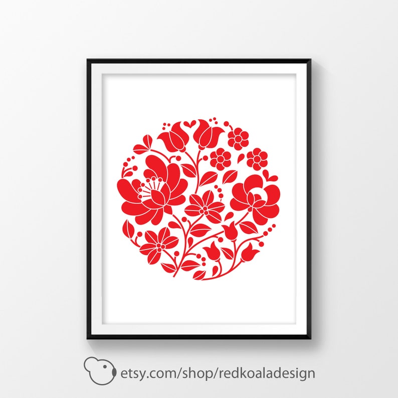May include: Red and white floral design in a circle, reminiscent of traditional folk art. The design is on a white background and framed in a black frame.