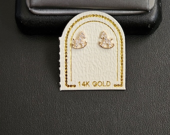 May include: A pair of 14k gold earrings featuring a rocking horse design with clear cubic zirconia stones.