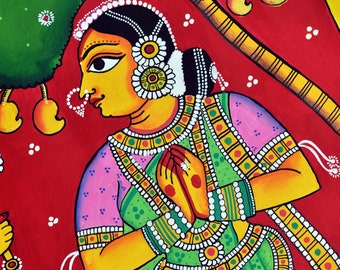 Può includere: Un dipinto tradizionale indiano che raffigura una donna in un sari verde e rosa con intricati gioielli d'oro. Lei è in piedi con le mani giunte in preghiera. Lo sfondo è rosso vivo con un albero verde e fiori bianchi.