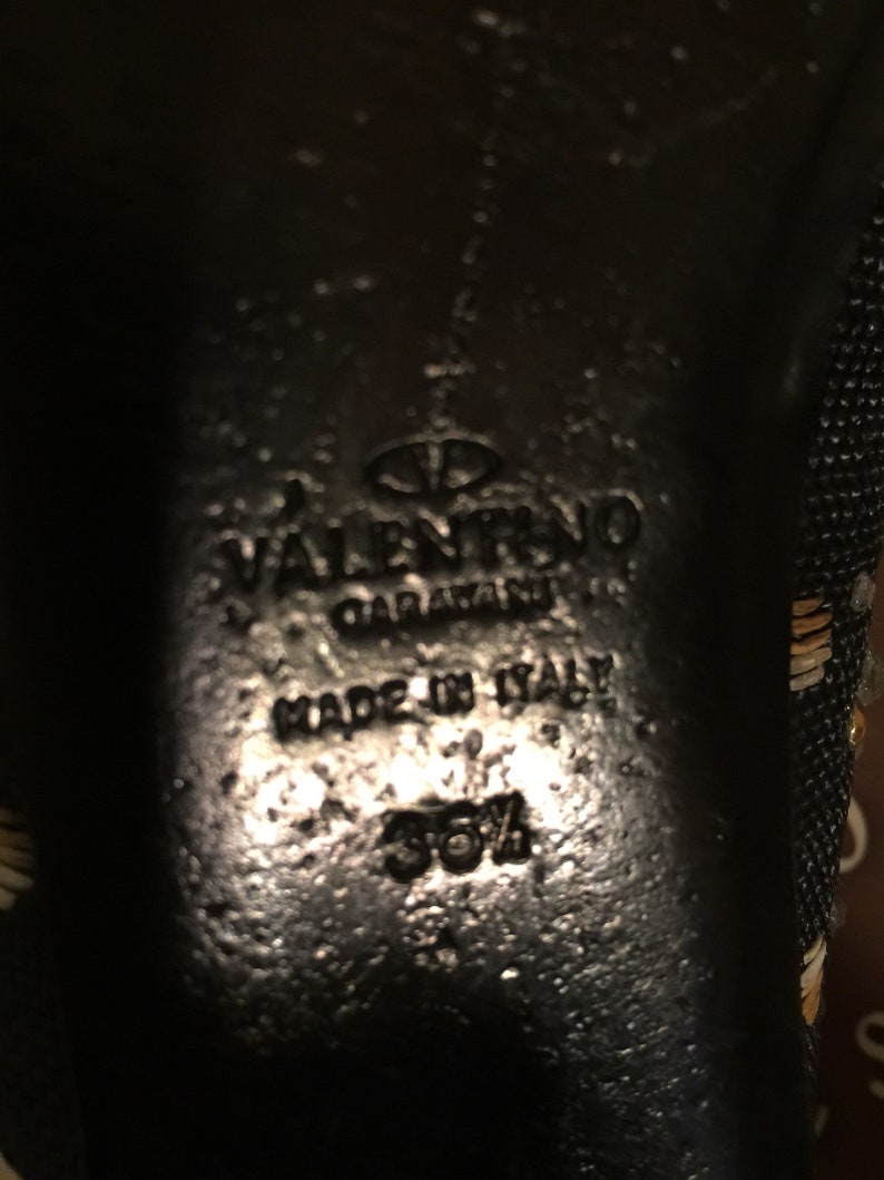 May include: Close-up of the bottom of a black shoe with the text "VALENTINO GARAVANI" and "MADE IN ITALY" in white. The size 35 1/2 is also visible.