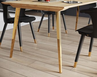 May include: A light wood dining table with gold-colored legs and black chairs. The table has a rectangular top and is surrounded by four black chairs with gold-tipped legs. The room has a modern design.