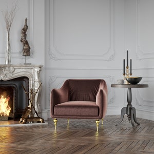 Puede incluir: Un sill&oacute;n de terciopelo marr&oacute;n con patas doradas en una habitaci&oacute;n con chimenea y una peque&ntilde;a mesa auxiliar. La silla tiene respaldo y reposabrazos redondeados. Una mesa negra con borde dorado sostiene un cuenco negro y candelabros.