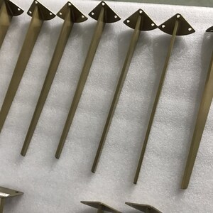 May include: Seven gold metal table legs with a triangular top. The legs are approximately 12 inches long.
