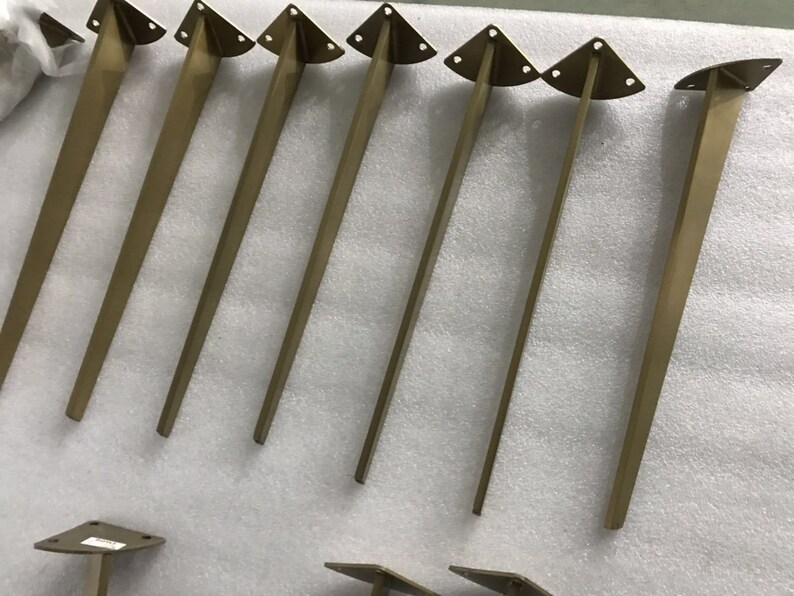 May include: Seven gold metal table legs with a triangular top. The legs are approximately 12 inches long.