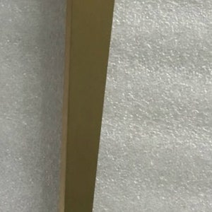 May include: A gold metal table leg with a flat top and a long, slender design.