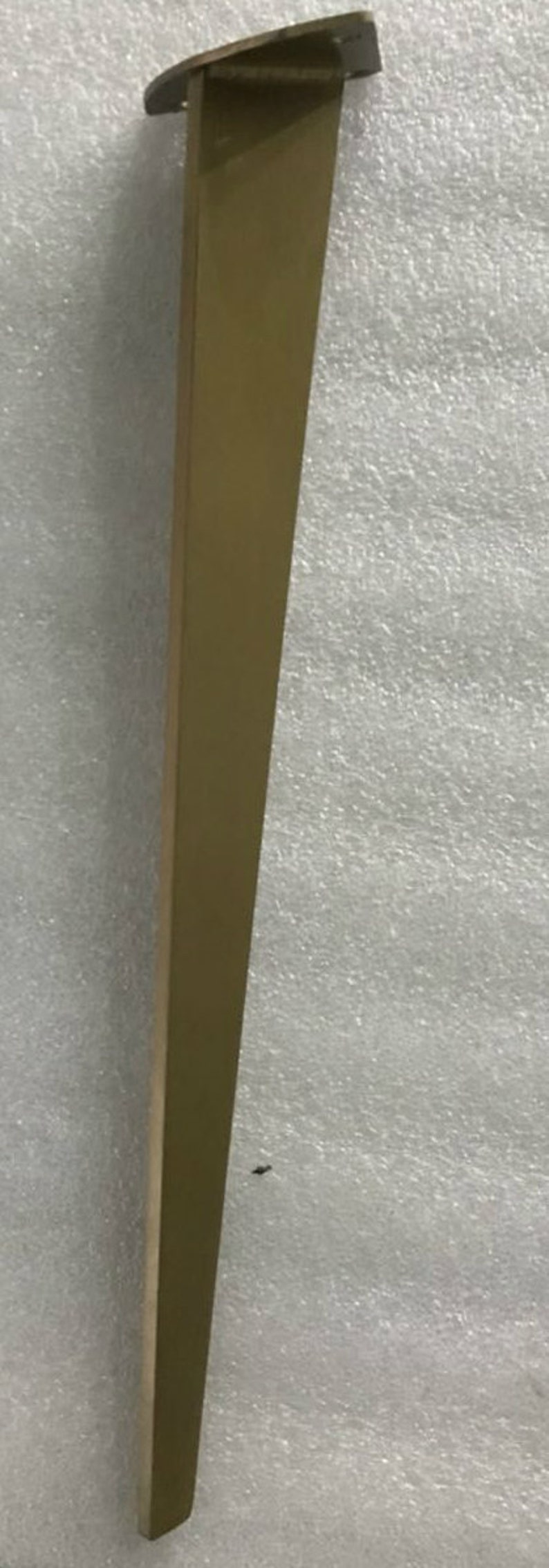 May include: A gold metal table leg with a flat top and a long, slender design.