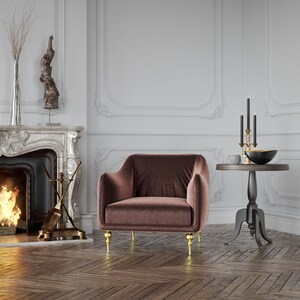 Puede incluir: Un sill&oacute;n de terciopelo marr&oacute;n con patas doradas se encuentra en una habitaci&oacute;n con chimenea y una peque&ntilde;a mesa auxiliar. La silla tiene respaldo y reposabrazos redondeados. La habitaci&oacute;n tiene un dise&ntilde;o cl&aacute;sico con chimenea y molduras decorativas.