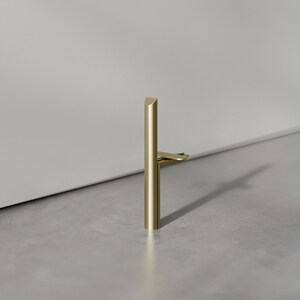 May include: A gold metal door stop with a rounded top and a flat base. The door stop is designed to prevent doors from slamming.