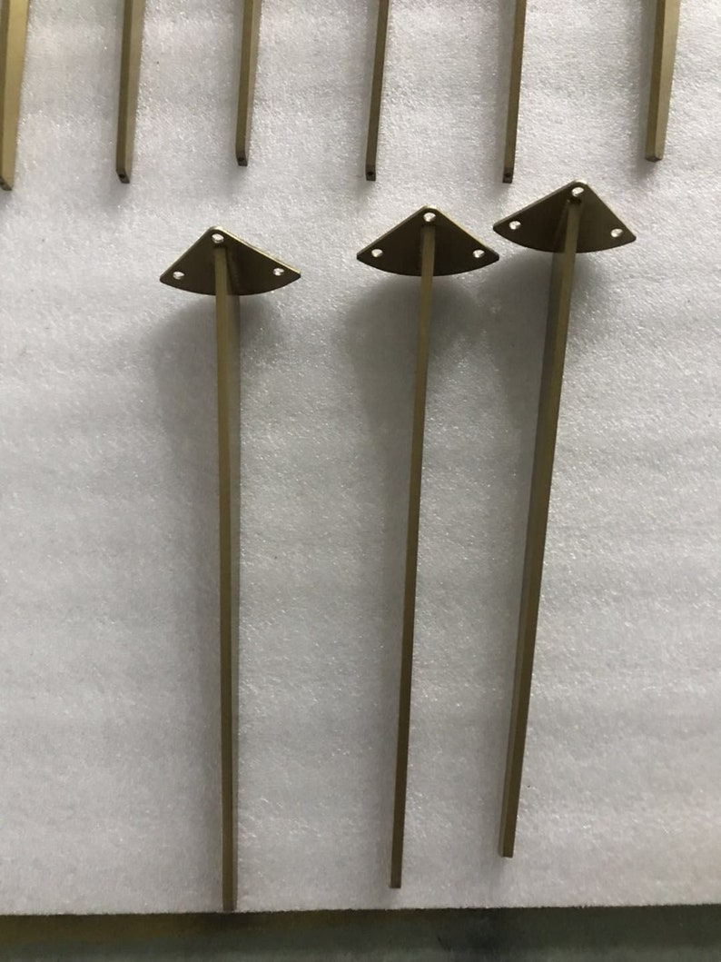May include: Three gold metal table legs with triangular bases. Each leg has three holes in the base.