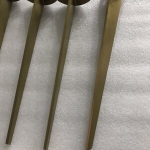 May include: Four gold metal table legs with a triangular top and three holes for mounting.