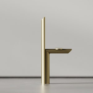 May include: A gold metal faucet with a single handle and a rectangular spout. The faucet is mounted on a white wall.
