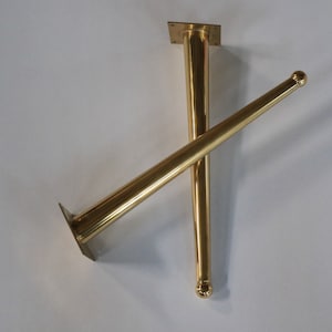May include: Two gold metal table legs, one with a square base and the other with a rounded tip.
