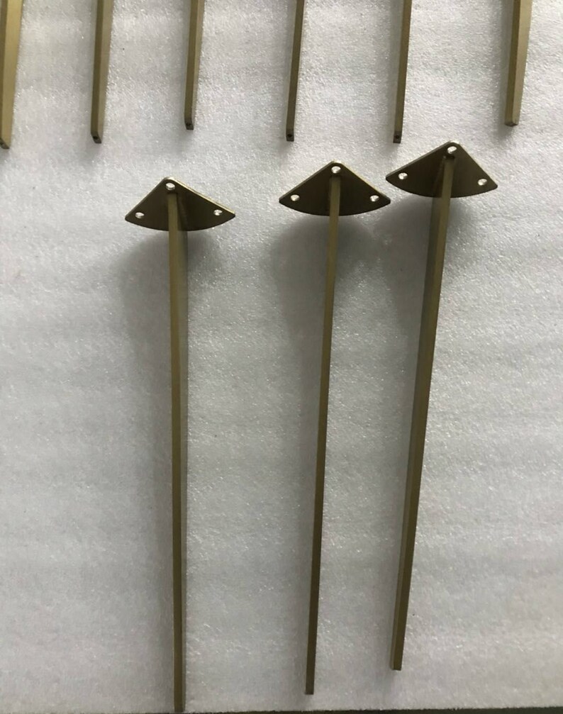May include: Three gold metal furniture legs with triangular bases. Each leg has three holes in the base.