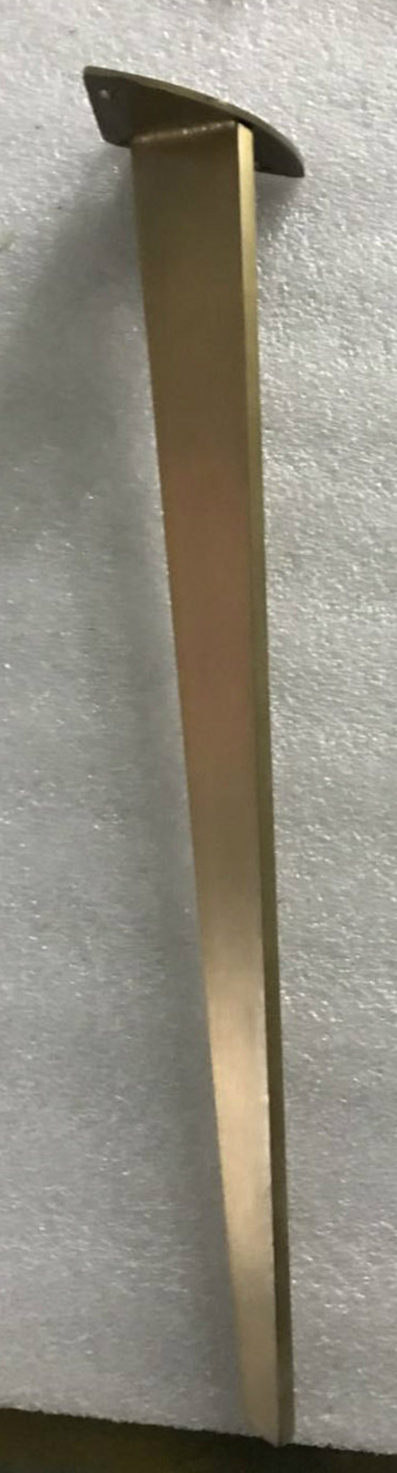 May include: A gold metal table leg with a triangular top. The leg is about 18 inches long.