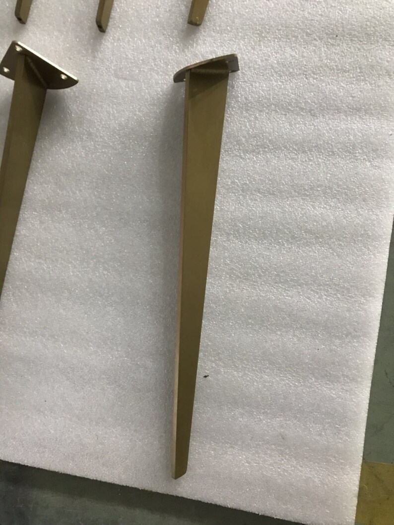 May include: A gold metal table leg with a triangular base. The leg is about 16 inches tall.