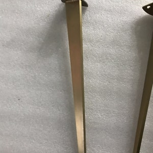 May include: Two gold metal table legs with a triangular top. The legs are about 28 inches tall.