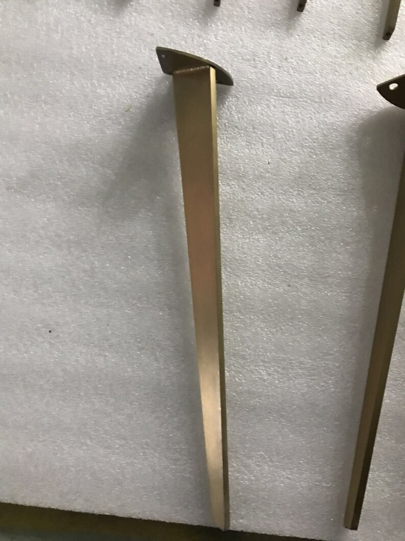 May include: Two gold metal table legs with a triangular top. The legs are about 28 inches tall.