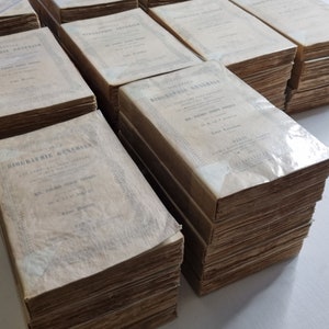 May include: A stack of antique books with the title "Biographie Generale" on the cover. The books are bound in brown leather and have a worn, aged appearance.