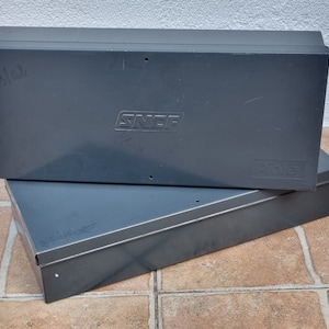 Puede incluir: Dos cajas de almacenamiento de metal gris apiladas una encima de la otra. La caja superior tiene la palabra "SNCF" impresa en ella. La caja inferior tiene la palabra "SNCF" impresa en ella.