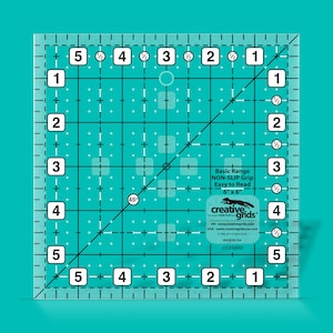 May include: A clear 6-inch by 6-inch ruler with a non-slip grip. The ruler has a grid pattern with 1/2-inch markings and a 45-degree angle line. The ruler is labeled "Basic Range NON-SLIP Grip Easy to Read 6" x 6" creative.grids".