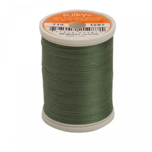 May include: A spool of olive green mercerized cotton thread with a white plastic core. The top label is orange and white, featuring the brand name Sulky, the number 713, 1287, 3016/317, a barcode, and instructions to use a 90/100 top stitch needle.
