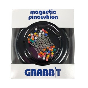 May include: A black magnetic pincushion with the text "magnetic pincushion" and "GRABBIT" on the packaging. The pincushion is filled with colorful sewing pins.