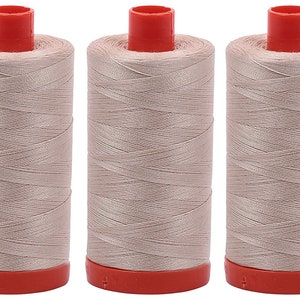 May include: Three spools of beige thread with red tops and bases. The thread is tightly wound around the spools, creating a textured appearance. Ideal for sewing, embroidery, or other crafts.