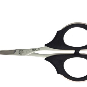 Może przedstawiać: Para małych, srebrnych nożyczek z czarnymi, gumowanymi uchwytami. Nożyczki mają małą śrubę w środku i napis "KAI 7100 Made in Japan" nadrukowany na boku.