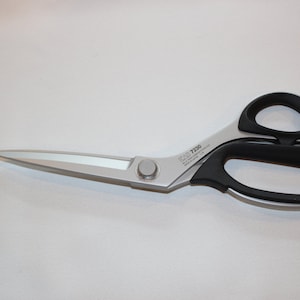 May include: Silver fabric shears with black handles. The shears have a silver screw adjustment and the text "KAI 7230" is printed on the side.
