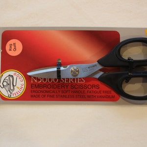 Puede incluir: Tijeras de bordado negras con una hoja plateada y mangos ergonómicos negros. El embalaje presenta el texto "N5000 Series Embroidery Scissors" y "Ergonomically soft handle, fatigue free. Made of fine stainless steel with vanadium."