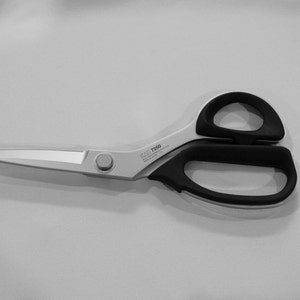 Może przedstawiać: Srebrne nożyczki do tkanin z czarnymi uchwytami. Nożyczki mają srebrny guzik na uchwycie, a na ostrzu nadrukowany jest tekst "GSD T720".