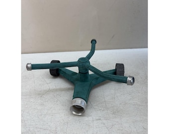 Aspersor de césped antiguo de hierro fundido con forma de mancha verde. Pulgar verde.