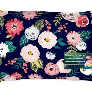 May include: A rectangular, navy blue therapeutic corn heating pad with a floral pattern. The pattern features pink, white, and coral flowers with green leaves. The pad has a tag with the text "Productive Parrott".