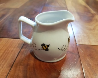 Cute little milk jug hand painted with gold and black bumble bees round the edge.