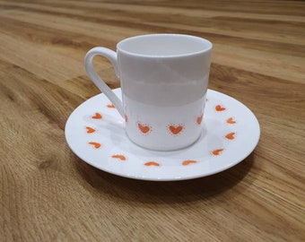 Taza de café espresso y platillo con corazones rojos