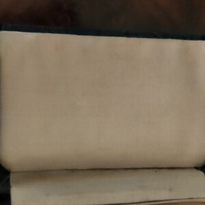 May include: A black leather-bound journal with a white interior. The journal is closed and the cover is visible.