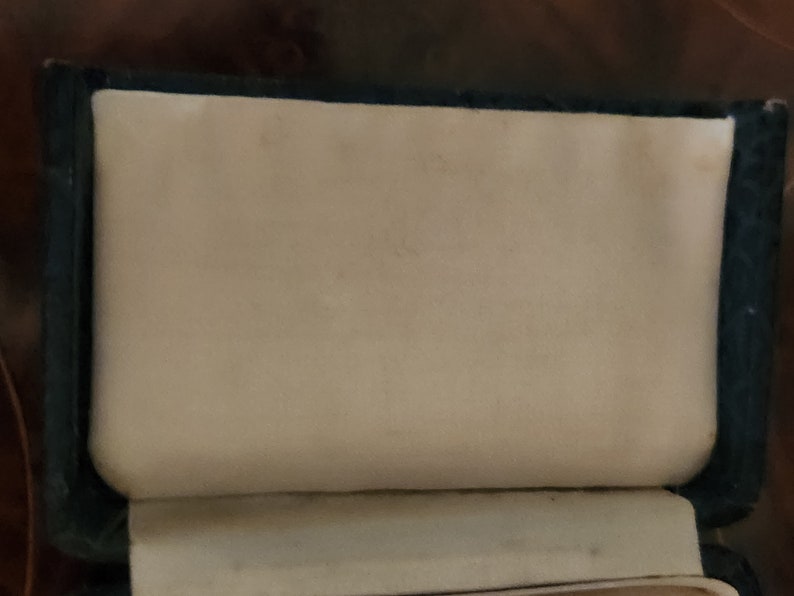 May include: A black leather-bound journal with a white interior. The journal is closed and the cover is visible.