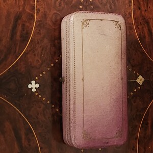 May include: A vintage, rectangular, purple and gold jewellery box with a decorative design on the lid.