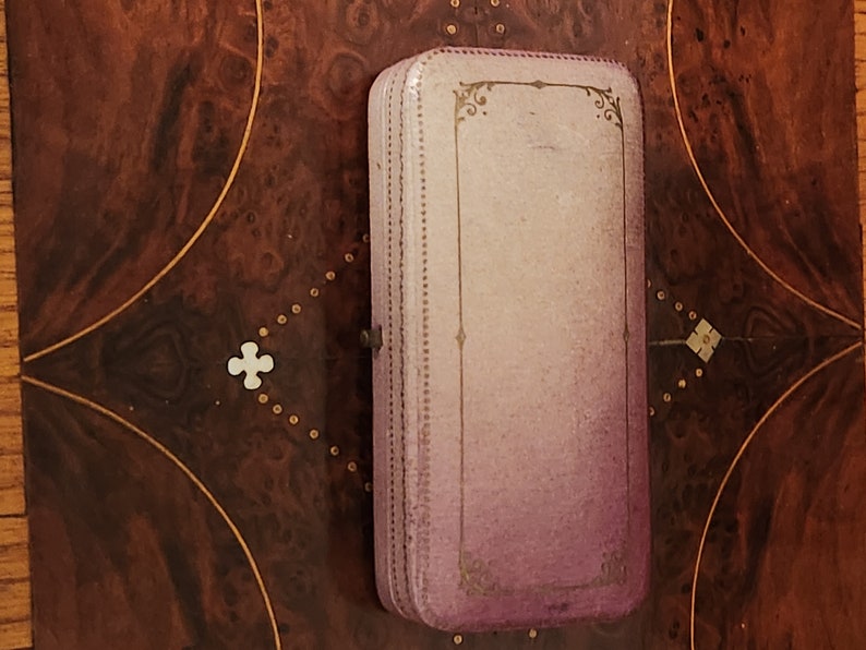 May include: A vintage, rectangular, purple and gold jewellery box with a decorative design on the lid.
