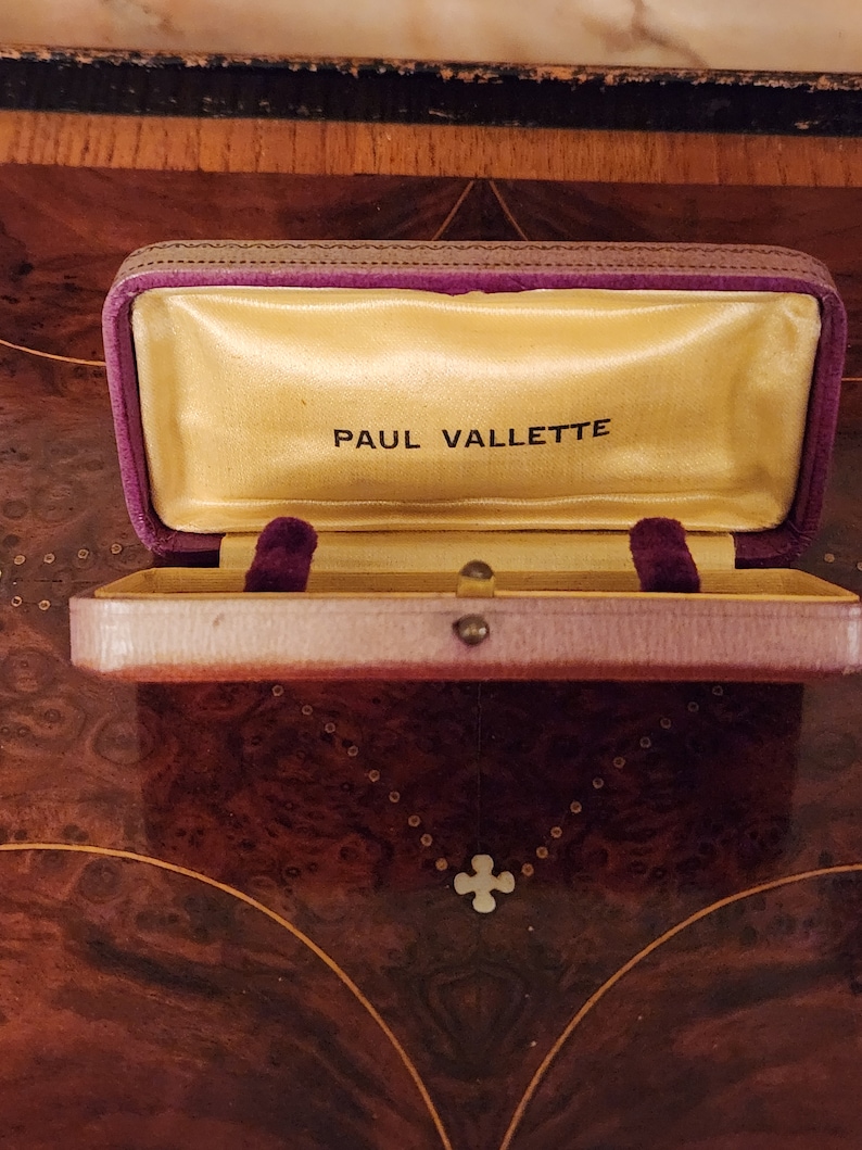 May include: A purple velvet jewellery box with a gold interior and the words "PAUL VALLETTE" printed on the inside.