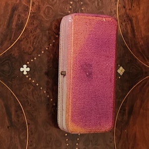 May include: A small, rectangular, pink and purple velvet jewellery box with a gold clasp.