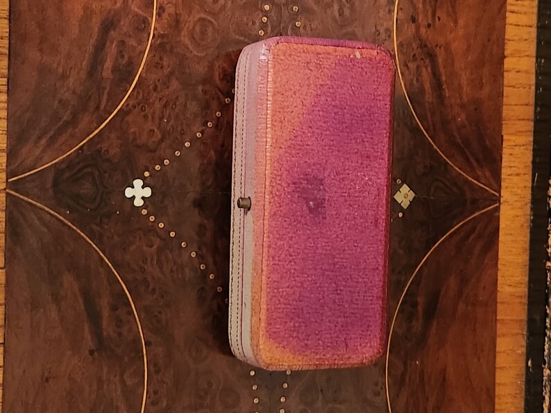 May include: A small, rectangular, pink and purple velvet jewellery box with a gold clasp.
